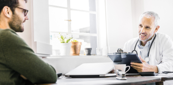 consultation entre un homme et un médecin autour d'un bureau